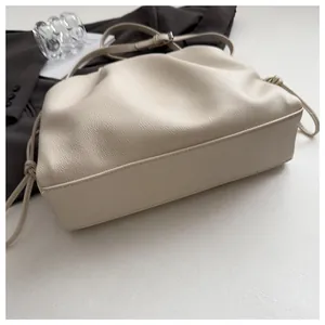 Detail of beige pleated leather crossbody bag with drawstring closure and soft texture