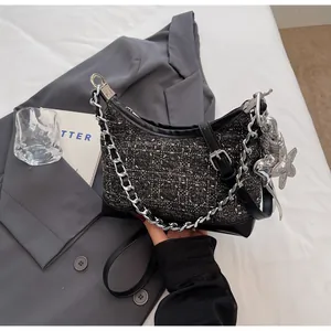 Detailed view of dark grey tweed crossbody bag with silver star charm and metallic chain