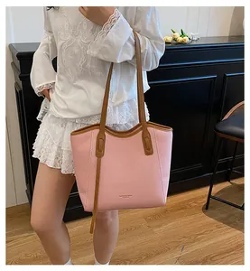 Pink woven tote bag with brown leather straps and fashion logo detail on the front