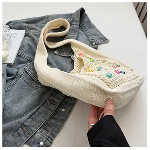 Close-up of cream knit tote bag with colorful beads on blue denim jacket background