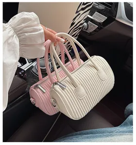 Detail of pink and beige pleated barrel bags with silver metal hardware in a car interior
