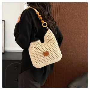 Detail van handgeweven tote bag met houten kralenband en leren patch logo