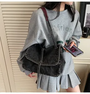 Detailed close-up of retro washed denim crossbody bag with contrast leather strap on a model