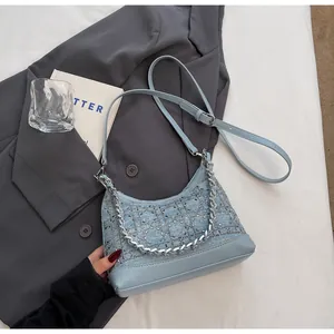 Close-up of denim blue bag with silver rhinestone cannage pattern and metal chain detail