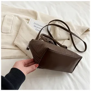 Gros plan sur la texture en damier tissé marron foncé et la base lisse du sac à main