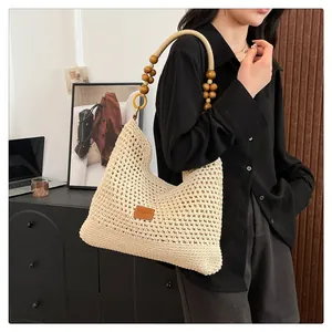 Detail van beige gehaakte draagtas met houten kralenband en leren patch versiering