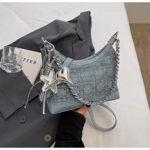 Detail of light blue denim handbag featuring sparkling rhinestones and metal charms
