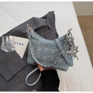 Detail of light blue denim crescent bag with metallic studs and silver star charm