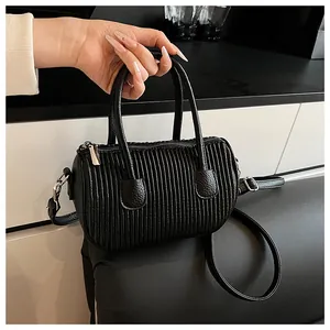 Detail of black cylindrical Boston bag featuring vertical pleated texture and silver hardware