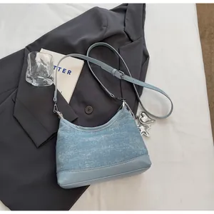 Close-up of light blue denim fabric handbag featuring metal heart and star charms