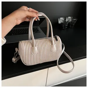 Detail of cream pleated cylindrical handbag with silver hardware and lychee grain leather