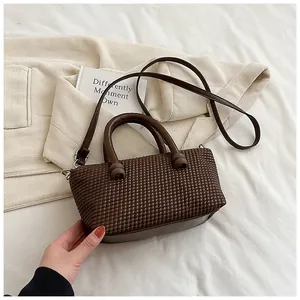 Détail de la texture tissée marron foncé du sac bandoulière avec finitions argentées