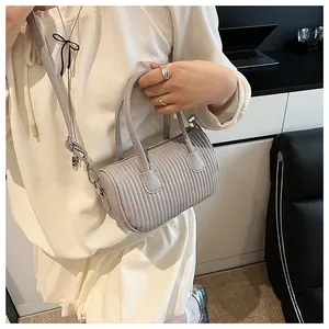 Detailed view of the pleated light grey cylinder bag with textured synthetic leather finish