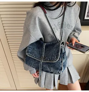 Detail of vintage blue denim tote bag featuring white stitching and metal buckle