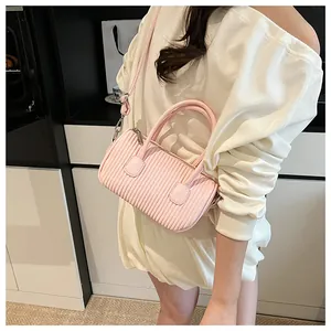 Detailed close-up of pink pleated textured shoulder bag worn by model in a modern room