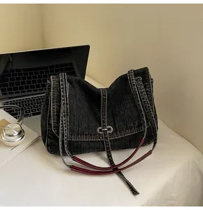 Detailed macro view of denim tote bag showing leather reinforced straps and metal buckle