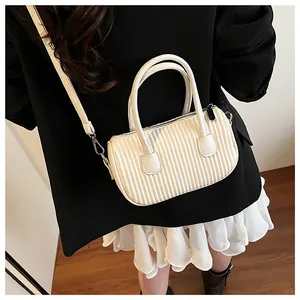 Detailed view of a white pleated mini crossbody bag worn by a model in a black blazer