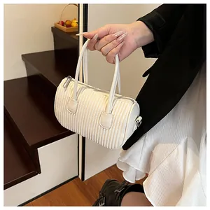 Detail of white pleated cylinder handbag featuring dual top handles and zipper closure