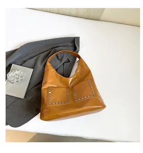 Close-up of caramel polished tote bag showing silver metal rivets and square front pockets