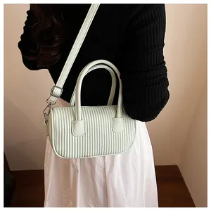 Detail showing mint green pleated cylinder bag with silver hardware and adjustable strap