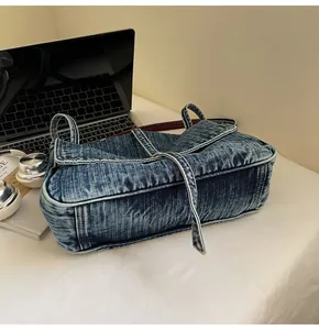 Detail of vintage washed blue denim tote bag with visible stitching and textured fabric
