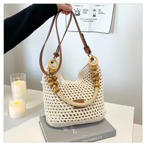 Detail van beige geweven draagtas met bruine leren riem en houten kralen accenten