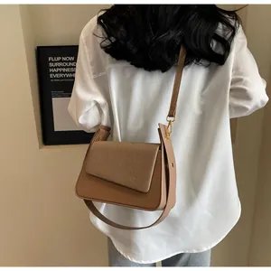 Détail du sac bandoulière en cuir kaki avec rabat tressé porté par un mannequin