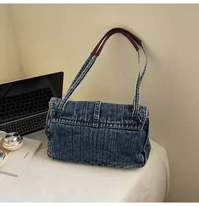 Detail of vintage denim tote bag with leather handles shown in a casual lifestyle setting