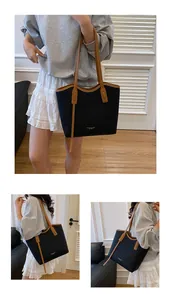 Detail of a large black leather tote bag with brown contrast straps and fashion lettering