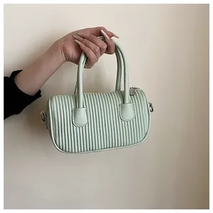 Detail of mint green cylindrical handbag with vertical pleated texture and dual handles