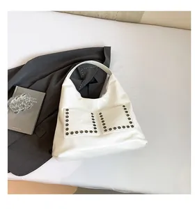 Detail of white leather crescent tote bag with hexagon rivets and double front pockets