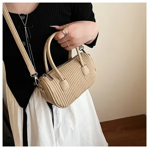 Detailed view of the vertical pleated texture on a retro beige cylinder crossbody bag
