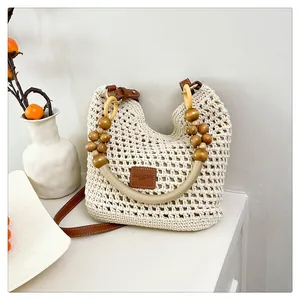 Detail van handgeweven draagtas met houten kralen handvatten en lederen logo-plaat