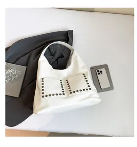 Detailed view of white hobo bag with silver hexagonal rivets on side pockets