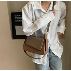 Détail d'un sac porté épaule vintage marron avec couture et boucle dorée sur modèle