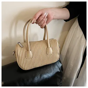 Detail of beige pleated cylinder handbag showing vertical texture and silver hardware