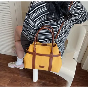 Dettaglio della borsa tote in tela gialla con manici in pelle marrone e tracolla