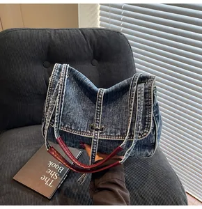 Detail of vintage denim tote bag featuring red leather handles and jacket-inspired stitching