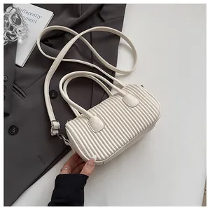 Detail of off-white cylindrical pleated handbag with adjustable shoulder strap and texture