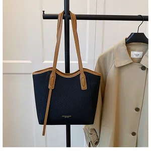 Detail of minimalist tote bag featuring black striped texture and brown leather strap