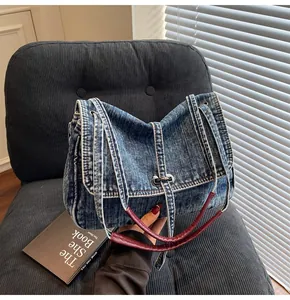 Detailed close-up of retro denim tote bag featuring metal twist lock and red leather handle