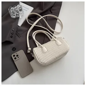 Detail of white cylinder pleated shoulder bag with soft leather texture and handle