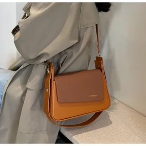 Détail du sac à bandoulière en cuir et tissu orange-marron avec boucle métallique dorée