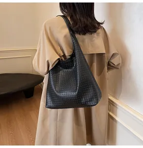 Détail de la texture tressée noire et de la bandoulière en cuir du sac hobo