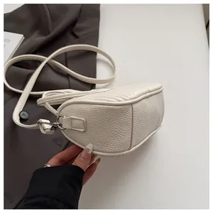 Close-up of white lychee texture leather shoulder bag with precision stitching and silver hardware