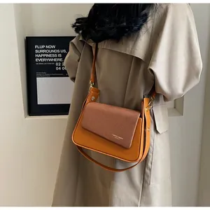 Détail du sac bandoulière en cuir caramel avec rabat en tissu et chaîne sur un mannequin