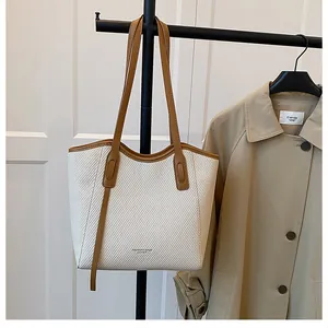 Detail of woven tote bag featuring brown leather straps and contrast color design