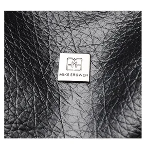Close-up of black textured leather handbag with a silver MIKE EROWEN brand logo plate