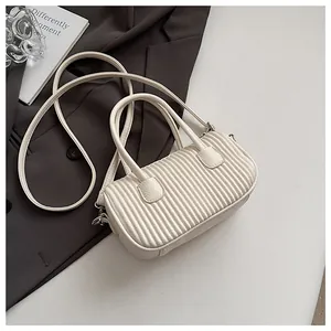 Detail of creamy white pleated texture on a faux leather cylindrical boston handbag