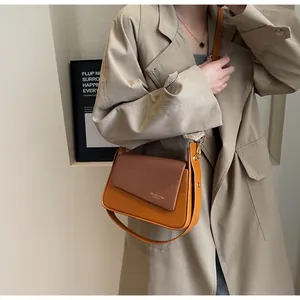 Détail du sac bandoulière vintage marron avec rabat texturé sur un trench-coat classique